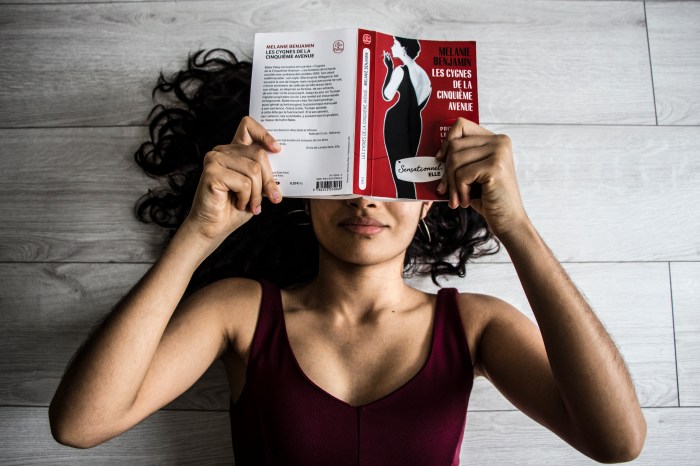 Chloé Andrianarisoa lisant Les cygnes de la cinquième avenue, allongée sur le sol © Chloé Andrianarisoa